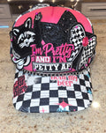 Pink and black checkered trucker hat with a raccoon patch, black sequin cat, checkered bow, 'I'm Pretty and I'm Petty AF' embroidered lettering, and a silver chain across the brim